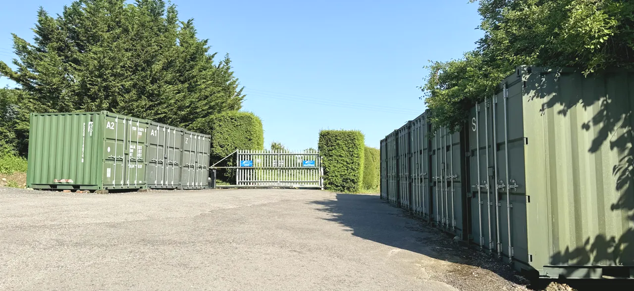 The gated entrance to Perry Storage seen from inside the yard, lined with containers